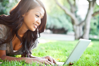 a female student laying on the grass with a laptop