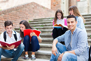 Smiling group of students studying together on outdoor campus steps.